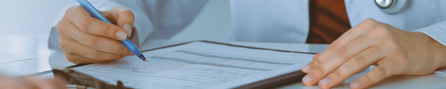 A doctor writing down on a clipboard on a table