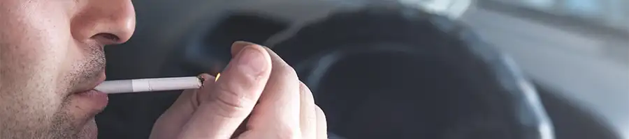 A picture of a man smoking marijuana inside the car