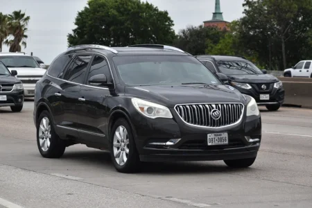 A portrait of a black Buick Enclave SUV traveling down a highway in moderate traffic