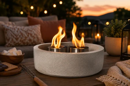 CHGBOWZ-style concrete tabletop fire pit with dual flames, marshmallows, and s’mores supplies on a patio at sunset.