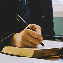 A lawyer writing down on a law book on an office table