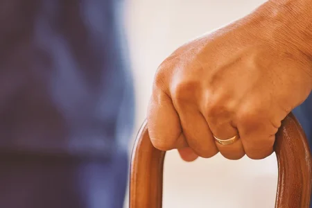 A person with parkinsons holding a cane
