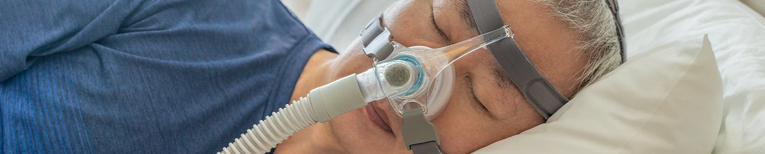 Man resting in bed while using CPAP Machine