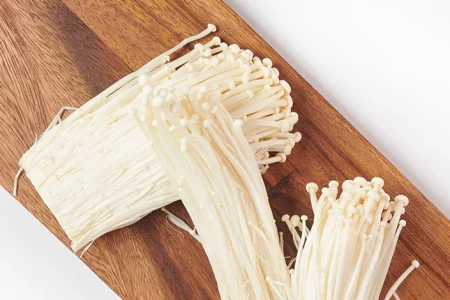 Enoki mushrooms on top of a cutting board