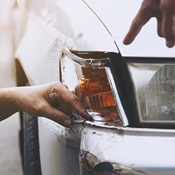 Two persons pointing to a corner of a car from a car accident