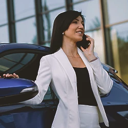 A woman on the phone while beside a car