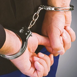 A close up shot of a criminal's hands in handcuffs