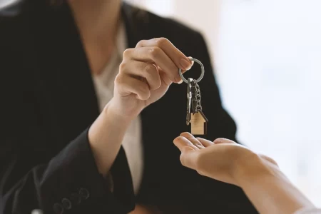 A person passing a mini house keychain