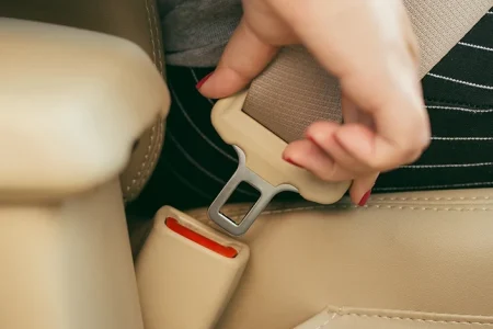 A close up shot of a woman removing her seatbelt