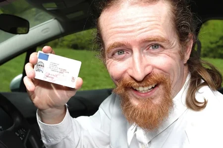 A man showing his driver's license while inside his car