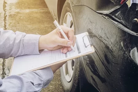 Insurance Adjuster checking damaged car