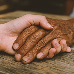 A person holding the hand of an old person
