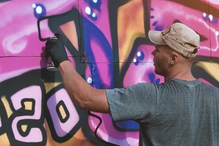 A graffiti artist committing vandalism on a wall