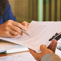 A person pointing to paperwork with a pen