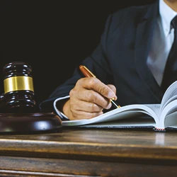 Close up shot of a lawyer writing on a book with a gavel on the side