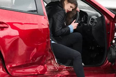 Woman inside a damaged red car