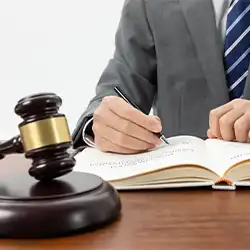 a photo of a person writing in a book with a gavel on the table