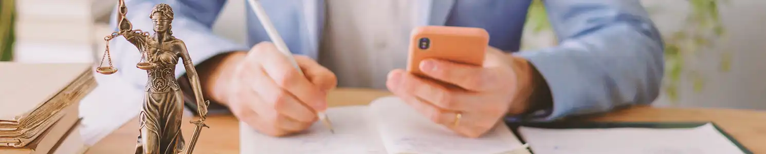 A person writing down notes while holding a phone