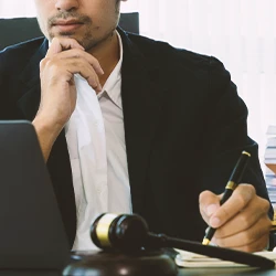 A lawyer looking at a laptop while writing down preponderance of the evidence vs beyond a reasonable doubt