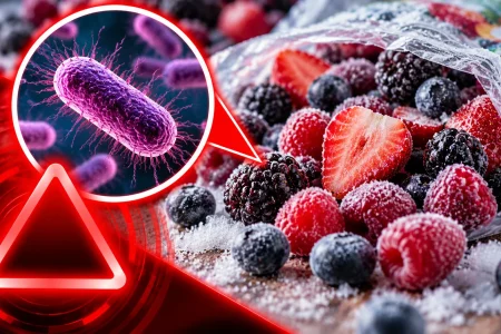 Frozen mixed berries beside a magnified bacteria inset and red hazard graphic illustrating the potential E. coli contamination risk.