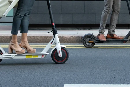 Two people riding an e-scooter in the road