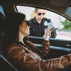 A woman getting a speeding ticket in a car