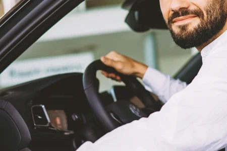 A person looking at the camera while driving a car
