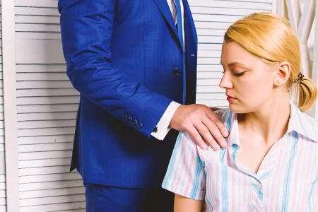 A man sensually holding a female coworker's shoulder