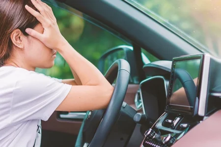 A woman with a headache driving a car