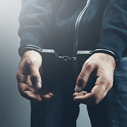 A close up shot of a man wearing handcuffs