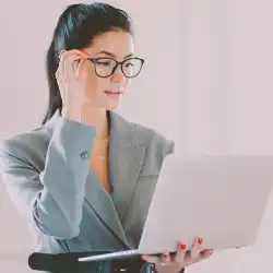 A business person holding and looking at a laptop while standing up
