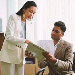 Two coworkers in an office discussing paperwork