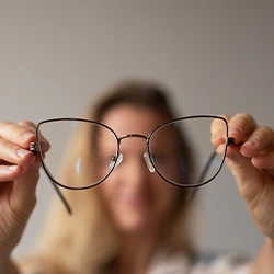 Woman holding glasses in front of the camera 
