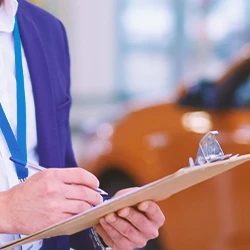 A person holding a clipboard in a car dealership