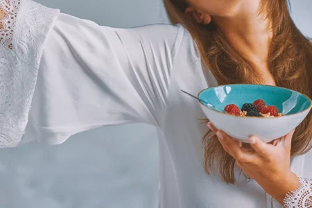 A woman holding a bowl of cereal that contains glyphosate