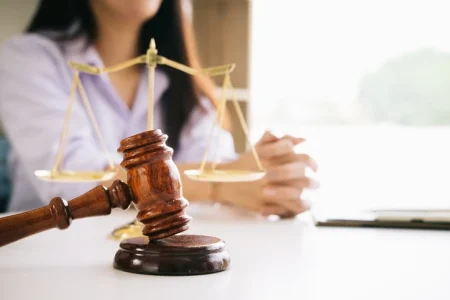 A judge's gavel and scale of justice in front of a woman