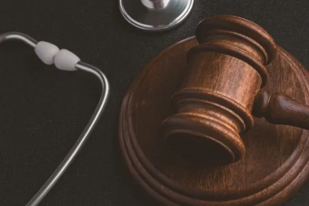 A stethoscope and a judge's gavel on a table side by side