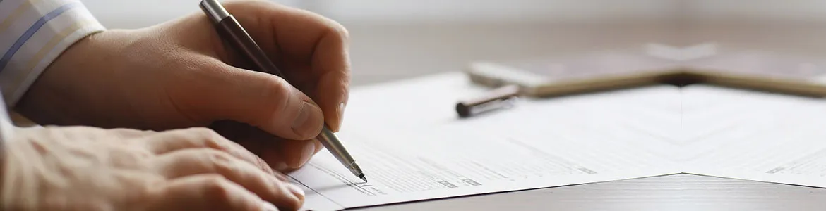 hand view of a man signing a paper