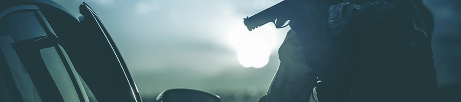 a man pointing a gun outside the car