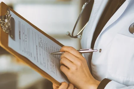 A doctor writing down on a clipboard